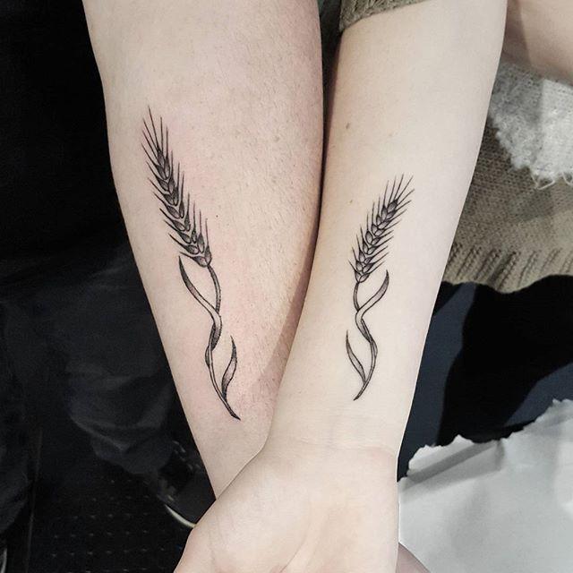 Tatuagem de ramo de trigo em tons de cinza no pulso.