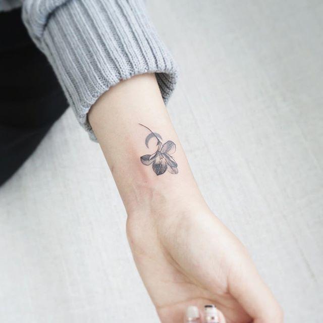 Tatuagem de flor em tons de cinza no pulso