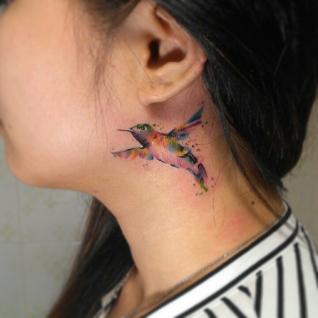 Tatuagem atrás da orelha feminina - Linda tatuagem aquarelada de um beija-flor.
