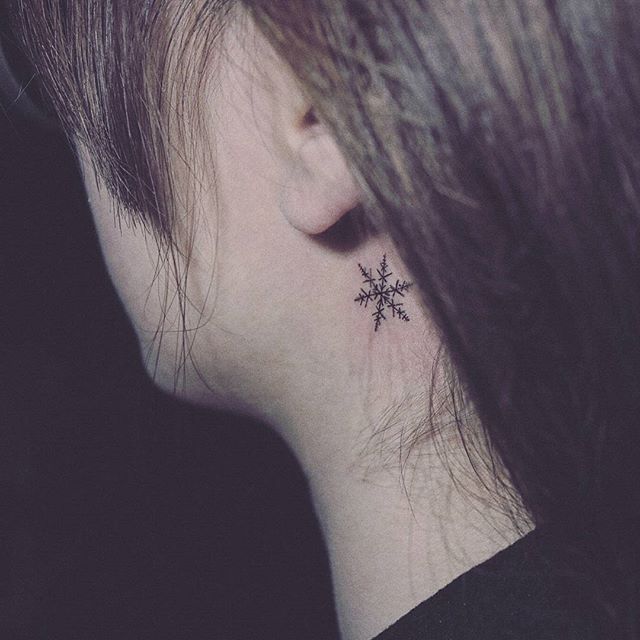 Tatuagem preta discreta e delicada atrás da orelha.