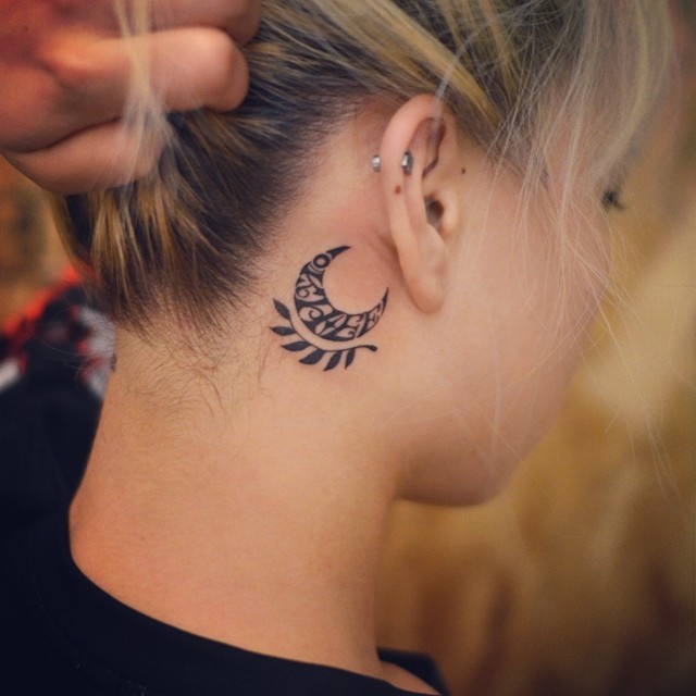Tatuagem de lua e ramagem atrás da orelha.