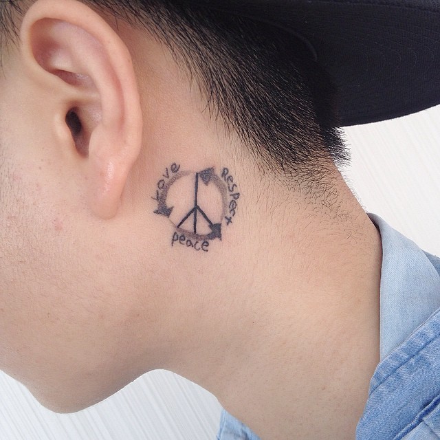 Tatuagem masculina atrás da orelha com o símbolo da paz e palavras em inglês.