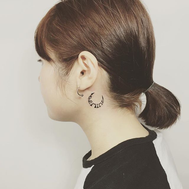 tatuagem delicada atrás da orelha com simbologia.