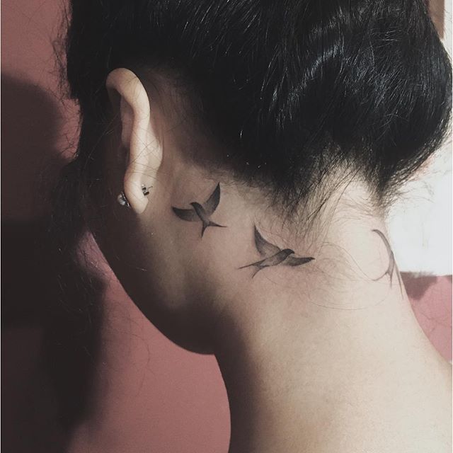 Tatuagem feminina atrás da orelha, pássaros discretos e elegantes.