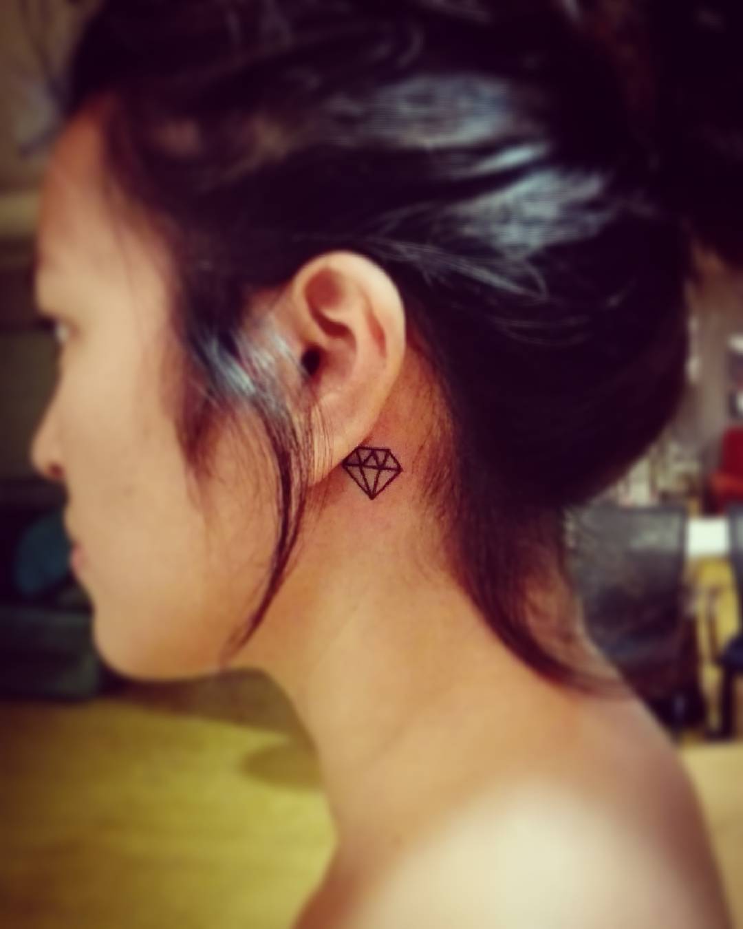 Tatuagem de diamante traçado atrás da orelha.