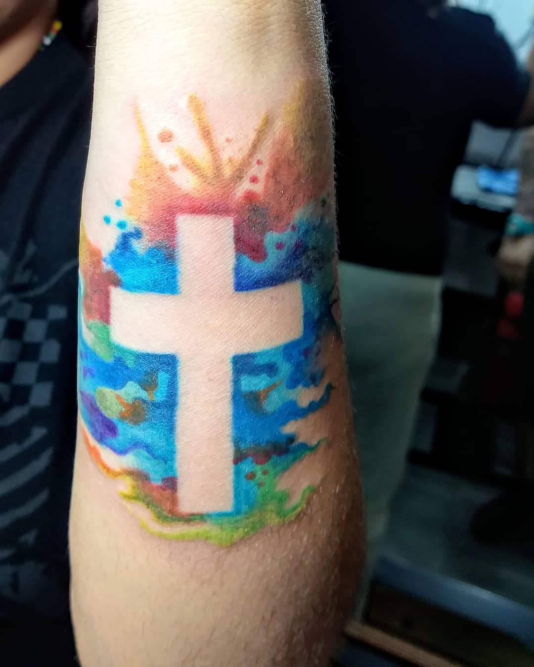 Tatuagem de cruz no braço em trabalho estilo aquarela
