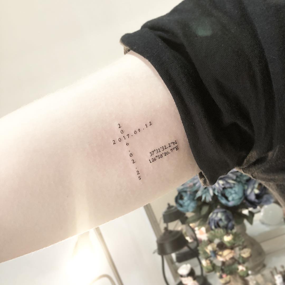 Tatuagem de cruz com datas e direções, muito criativa e delicada para todas as idades