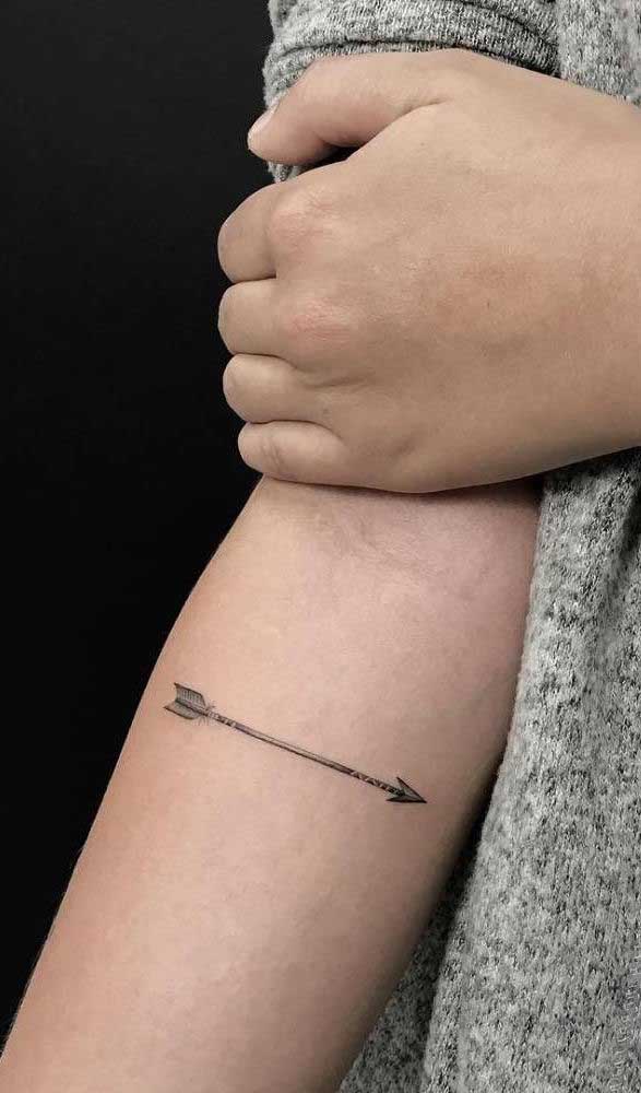 Uma tatuagem de flecha simples e de traços finos.