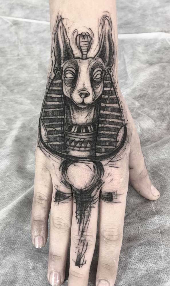 A Cruz Ansata e Anúbis ilustram a mão feminina nessa outra inspiração de tatuagem egípcia 
