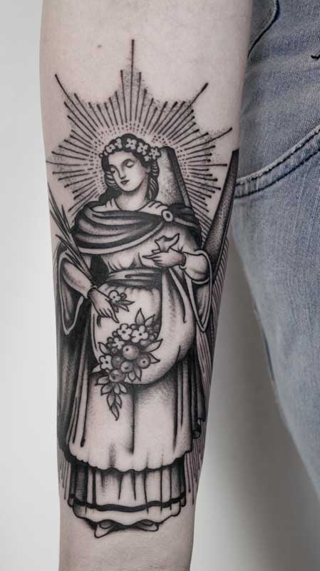 Tatuagem de santa com flores e arco de luz