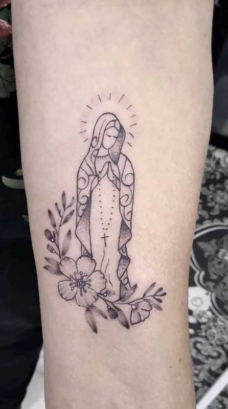 Aqui, a tatuagem de Nossa Senhora de Fátima aparece em estilo minimalista e delicado