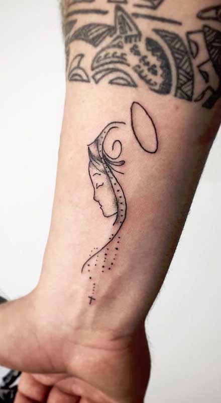 Tatuagem de santa delicada em contraste com a tattoo que fica um pouco mais acima
