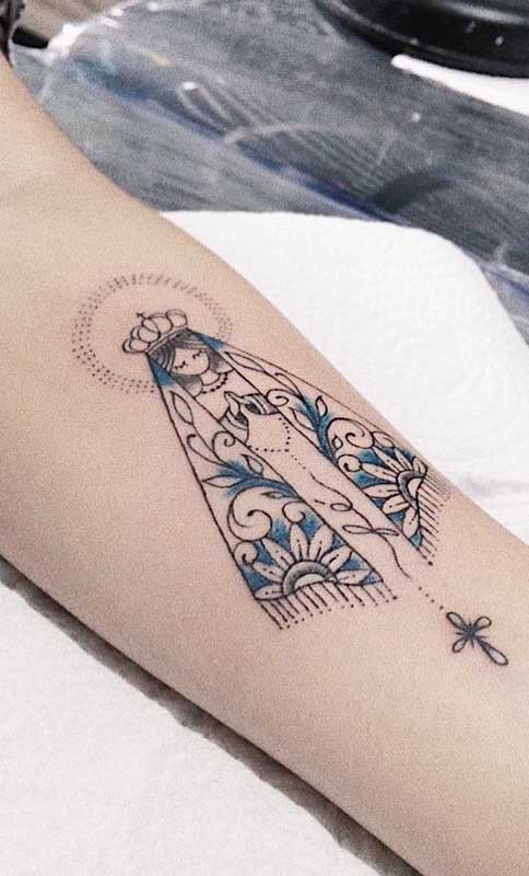 Tatuagem de santa no braço com contorno preto e preenchimento parcial azul