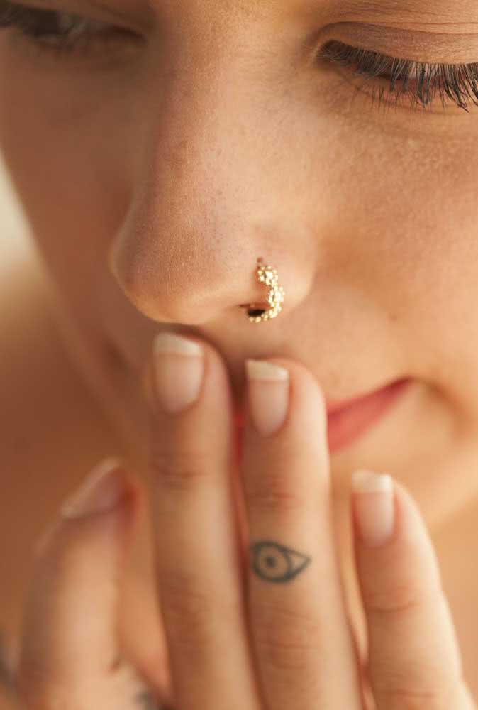Piercing de argola dourada no nariz para um visual mais delicado 