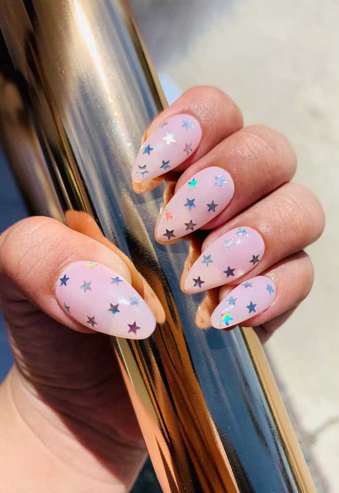 Jovial, divertida e muito fácil de fazer: unha stiletto com esmalte rendinha e aplicação de adesivos holográficos de estrelas. 