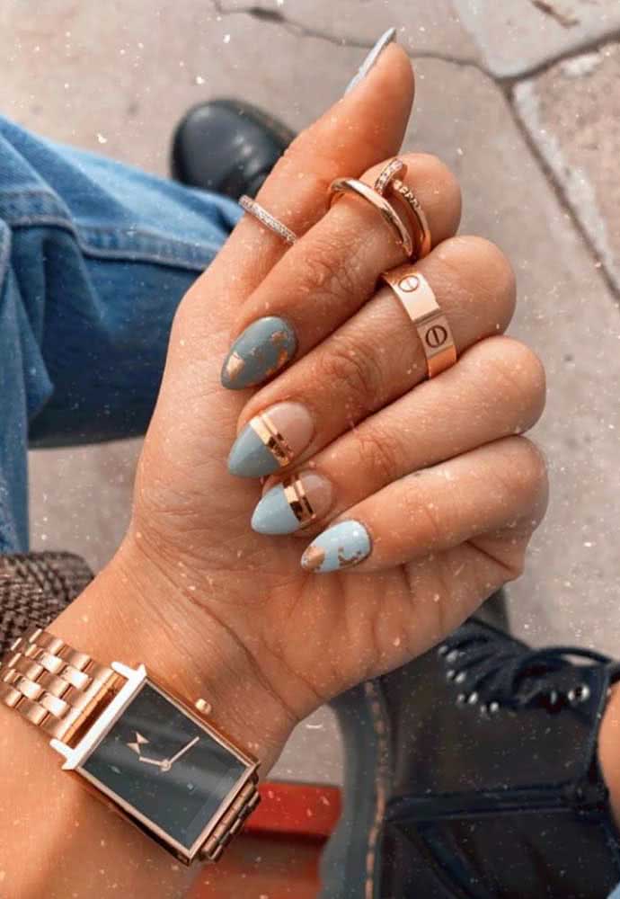 O dourado delimita a half nail azul com duas faixas nas unhas gêmeas e dá um toque a mais de elegância para as demais nessa composição. 