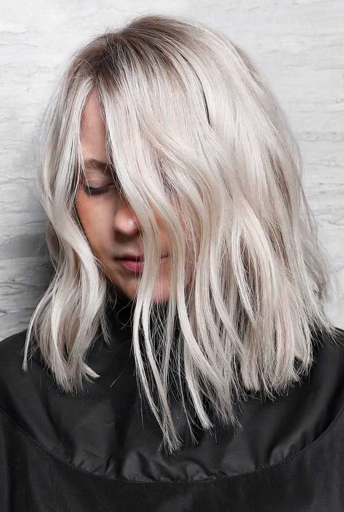 Cabelo platinado de comprimento médio e corte simétrico.