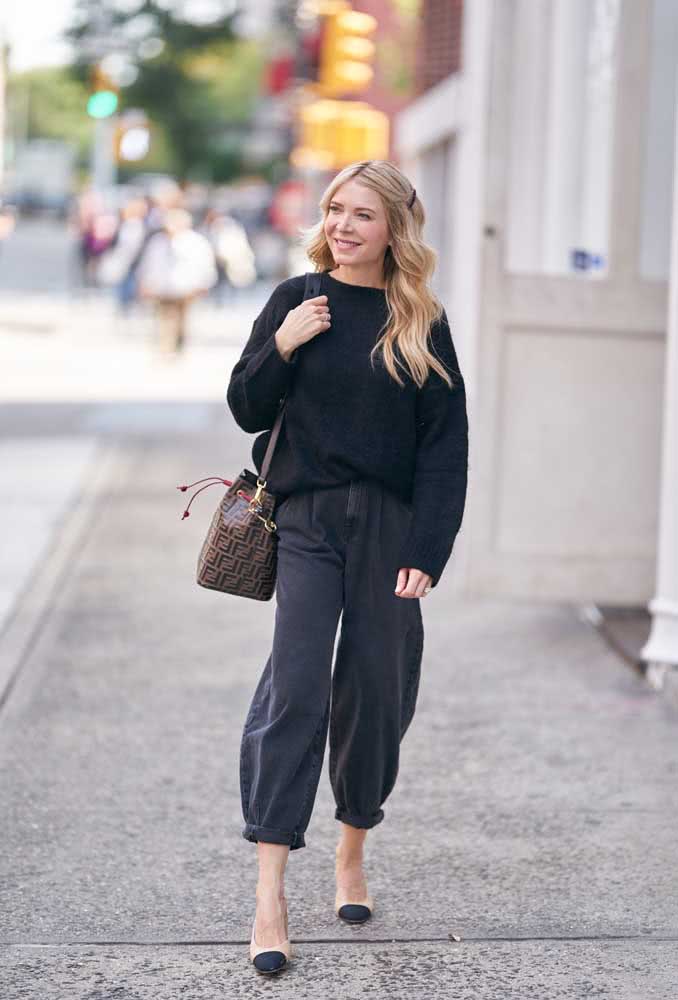 Para equilibrar o visual nesta combinação de calça boyfriend com suéter oversized pretas, uma sapatilha bicolor delicada.