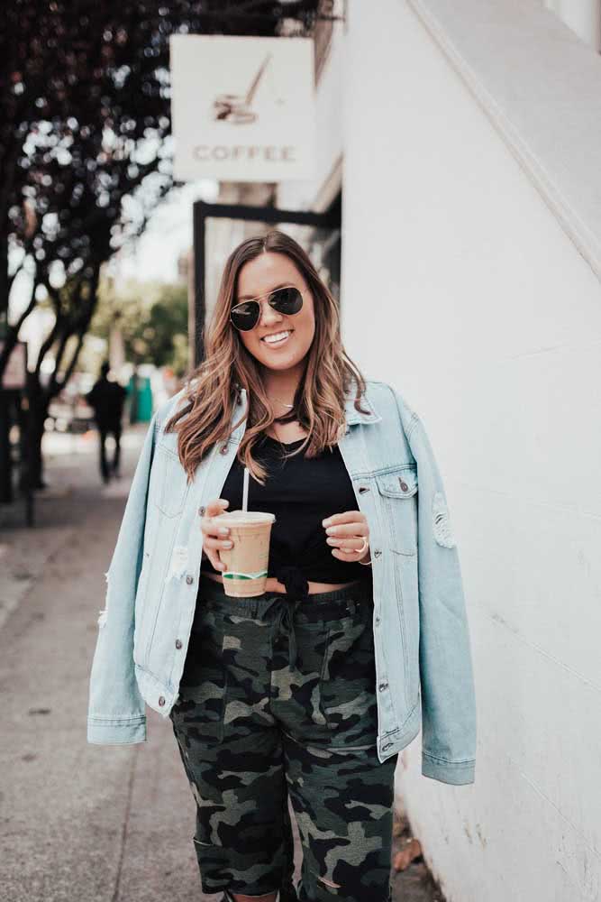 Uma jaqueta larga jeans completa o look despojado com calça camuflada