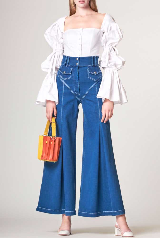 Um look que brinca com o volume e movimento das peças com calça pantalona jeans de cintura alta e blusa de manga comprida bufante.