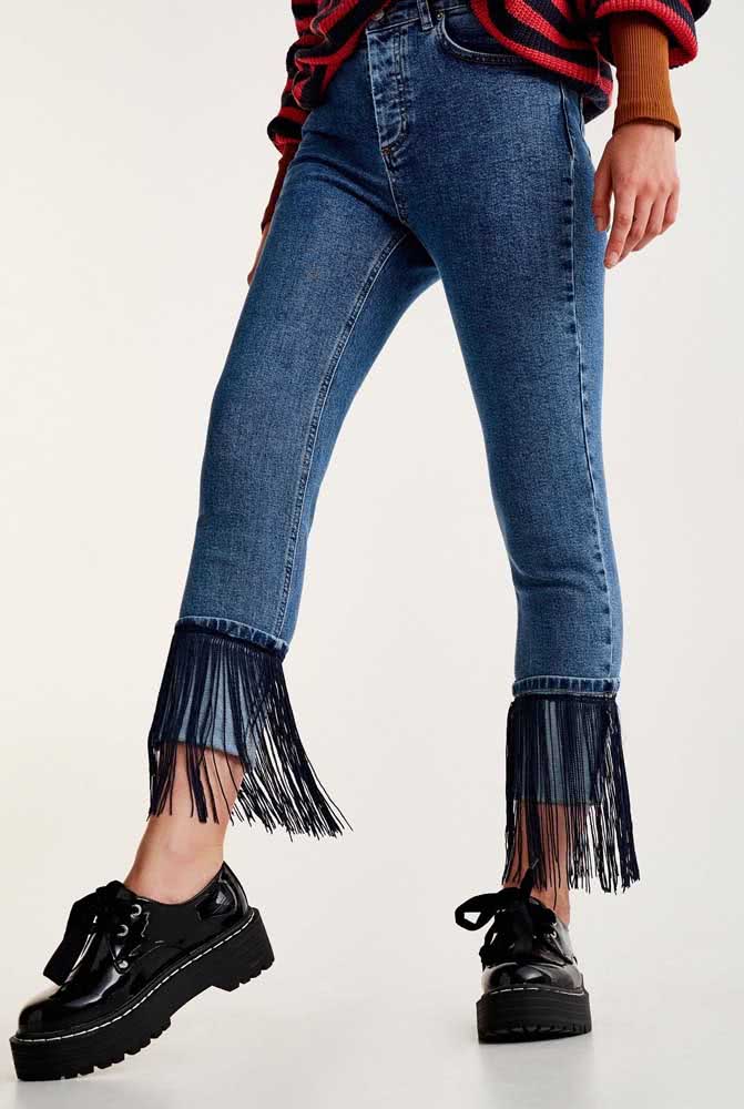 Calça jeans com a barra customizada de franjas