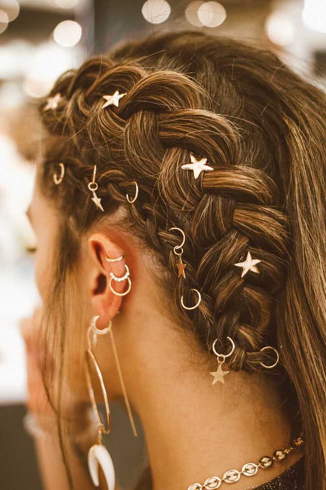 Em primeiro lugar, um penteado com um lado solto e outro feito com trança embutida decorada com anéis estrelados que tem tudo a ver com os brincos usados. 