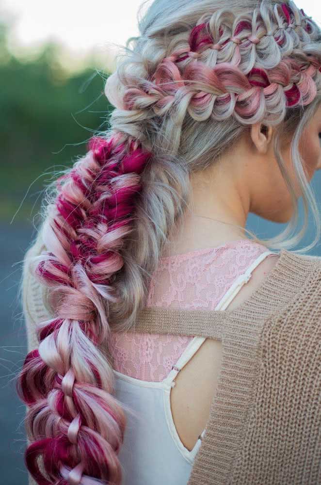 Um penteado cheio de detalhes em cabelo platinado com um toque de rosa que mistura trança embutida falsa na parte de cima e trança escama de peixe ao longo do comprimento. 