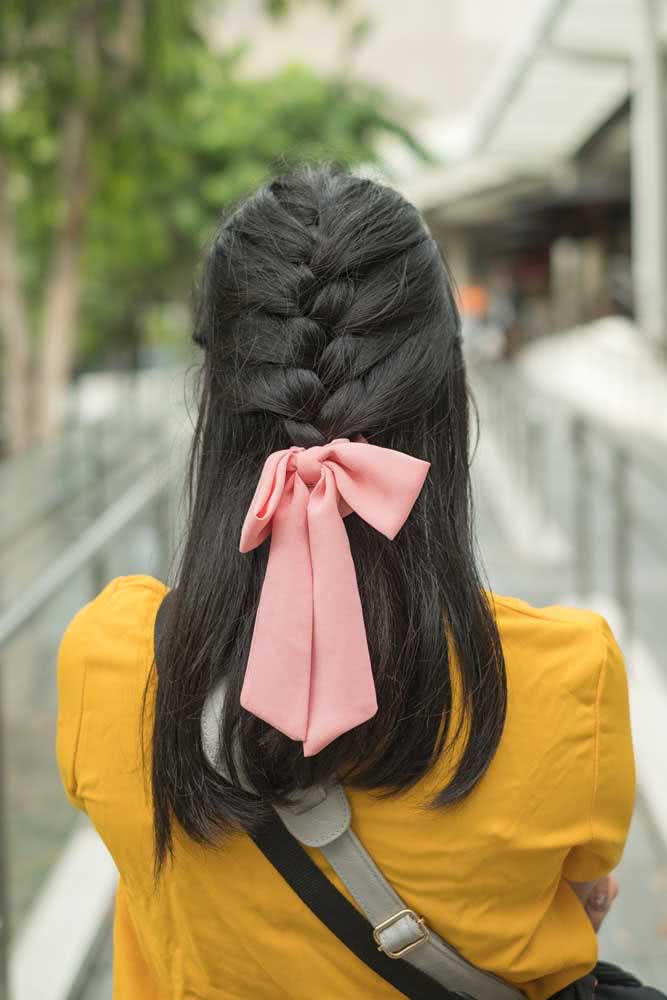 Trança embutida somente até o meio do cabelo, presa com uma fita rosa: um penteado simples e cheio de charme para usar em qualquer ocasião. 