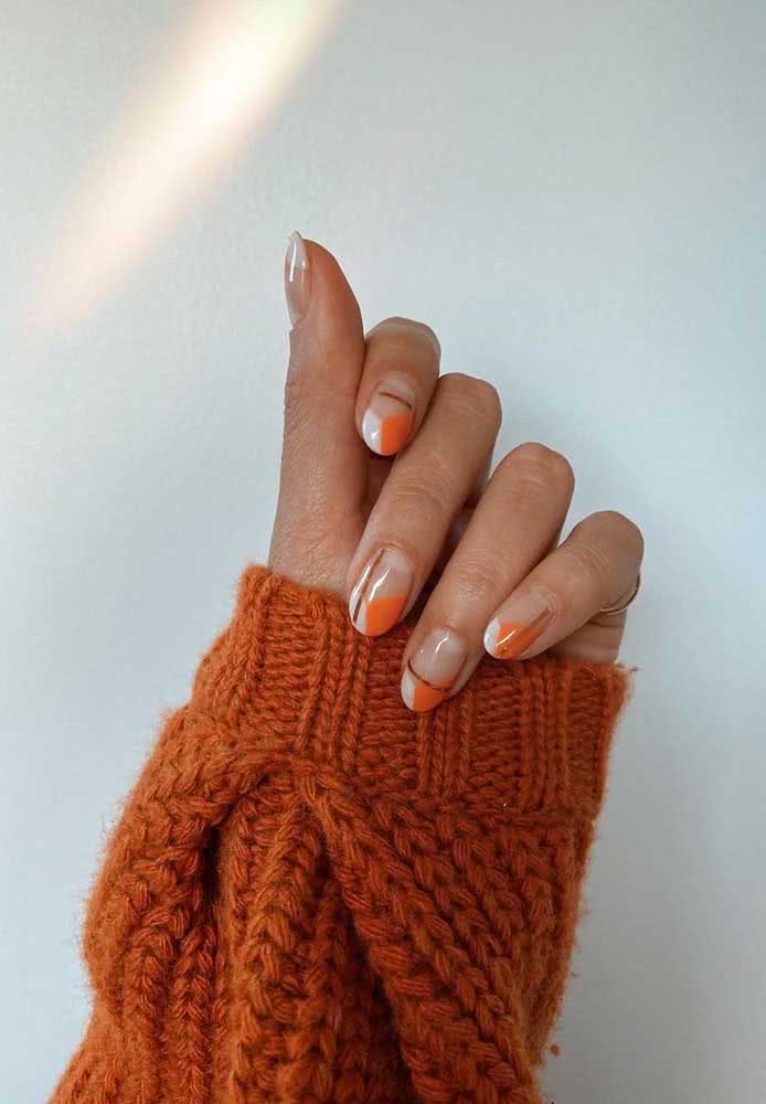 Seguindo o mesmo princípio, mas de maneira diferente: uma composição em branco e laranja nas pontas das unhas e um risco em cobre às vezes na horizontal e às vezes na vertical.