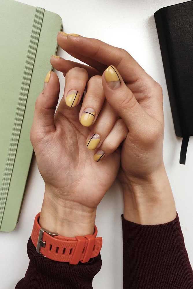 E para quem gosta de unhas gráficas, confira essa ideia de half nails em mostarda com linhas finas predominantemente verticais pretas.