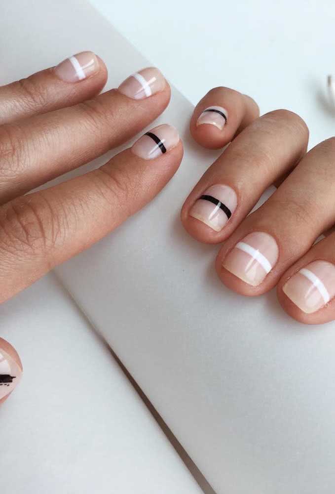 Um exemplo de unhas curtas decoradas simples com fundo clarinho e faixas preto e brancas na horizontal. 