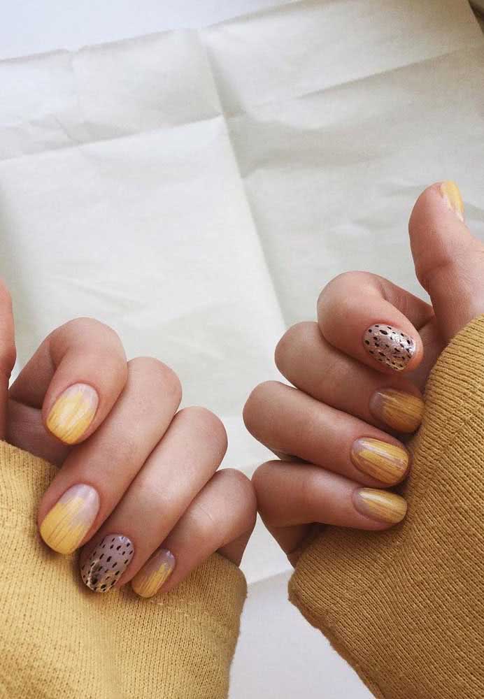 Pinceladas douradas e prateadas sobre as unhas pintadas com base transparente