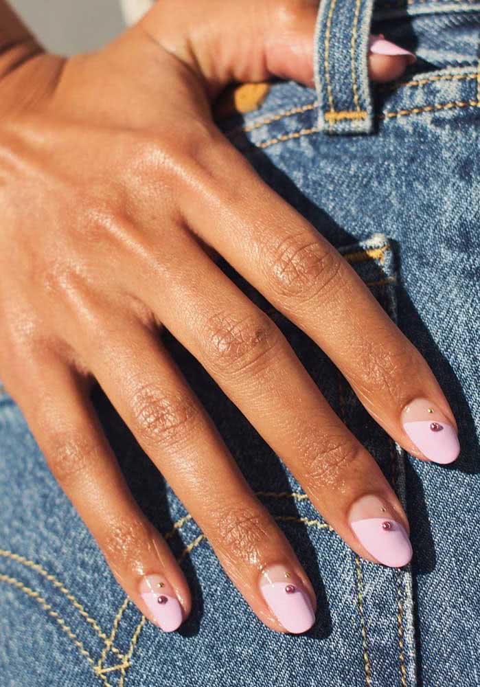 Half nail pintada em lilás e rosinha com divisão diagonal e uma pedrinha redonda como toque final.