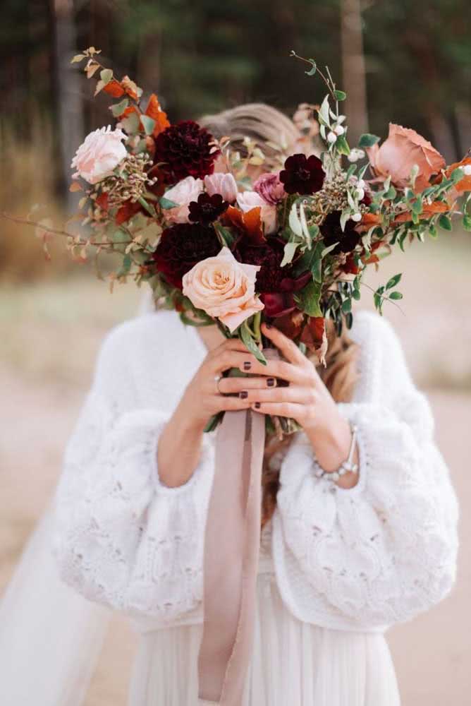 Por outro lado, o esmalte escuro deste exemplo de unhas de noiva curtinhas foi escolhido justamente para combinar com as flores do buquê.