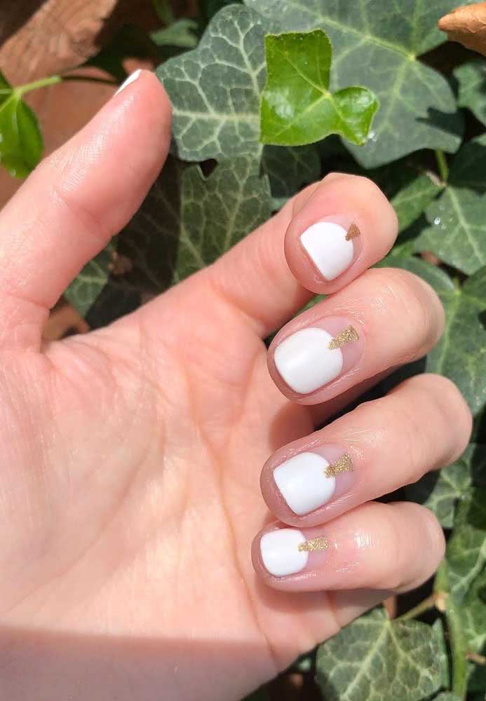 Outra ideia interessante de unha gráfica para noiva, com uma half nail branca arredondada que encontra um triângulo dourado com glitter que vem da área próxima à cutícula. 