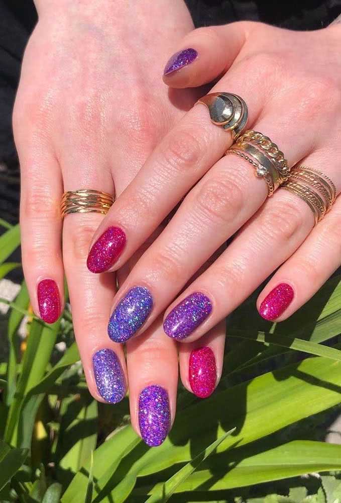 Glamour e diversão nestas unhas multicoloridas em tons de azul, roxo e rosa com acabamento de glitter.