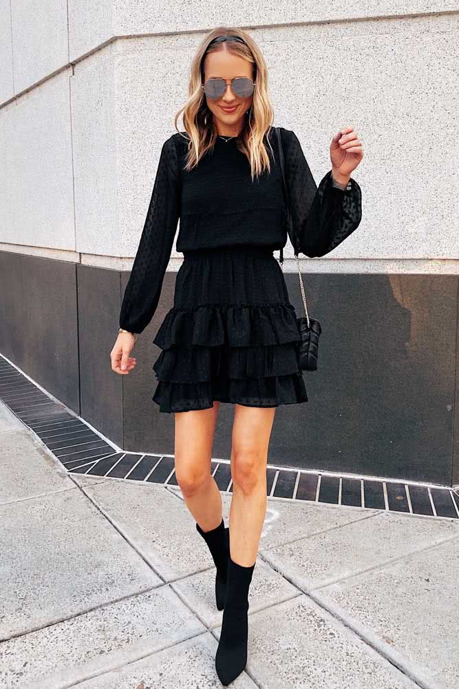 Vestido curto com manga longa super delicado e bota num look de festa preto.