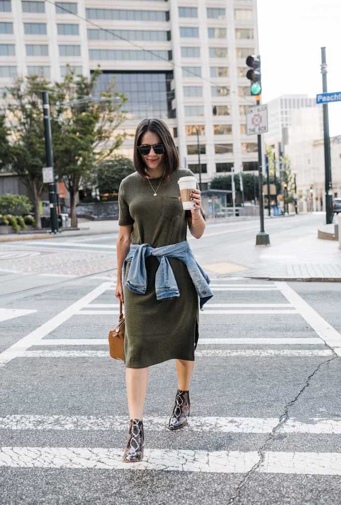 Vestido camisetão verde, jaqueta jeans e uma bota cano curto com estampa de cobra, uma combinação prática e estilosa para onde quer que você vá. 