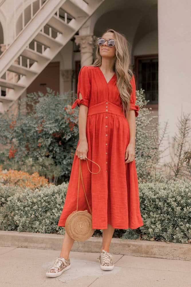 Outra opção para curtir um dia tranquilo de sol é com este vestido midi vermelho com tênis casual com estampa de oncinha.