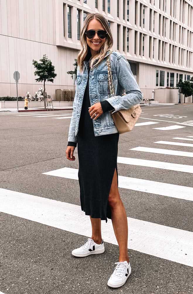 Vestido tubinho grafite midi com fenda lateral, jaqueta jeans e tênis branco criam um look descontraído para um passeio na cidade. 