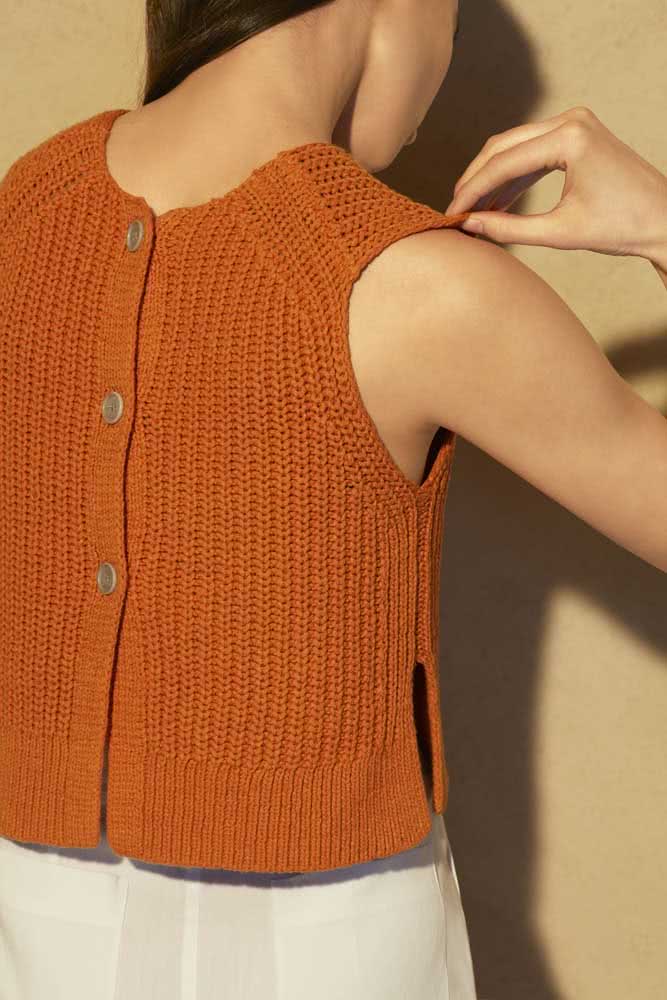 Cheia de elegância e sofisticação, uma blusa de crochê sem mangas e com botões nas costas.