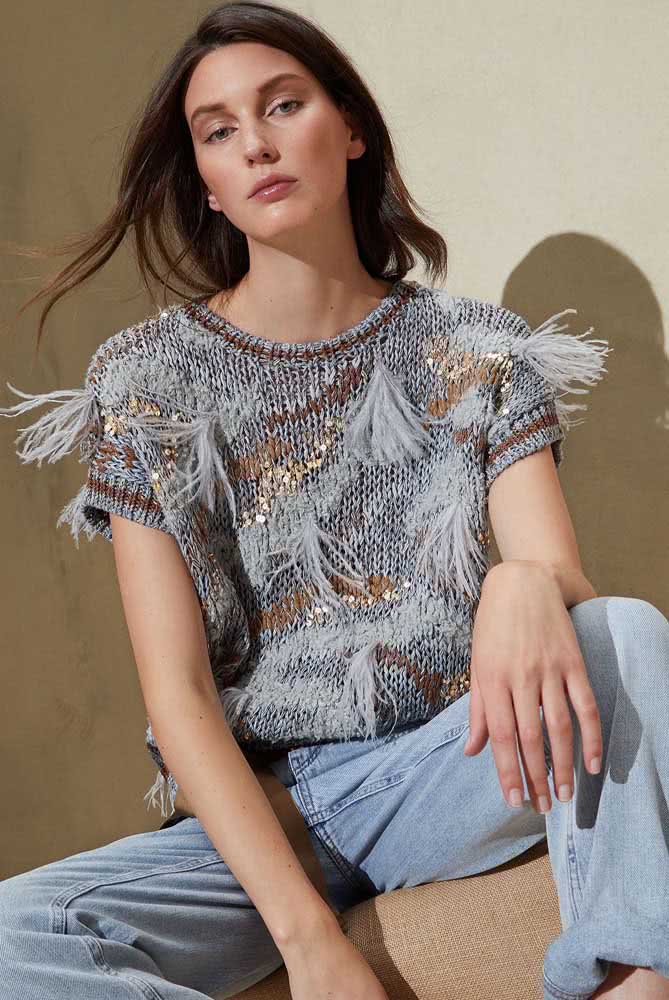 Um modelo de blusa de crochê cinza com detalhes em marrom e dourado, além de aplicação de franjas localizadas: uma escolha para arrasar em qualquer ocasião.