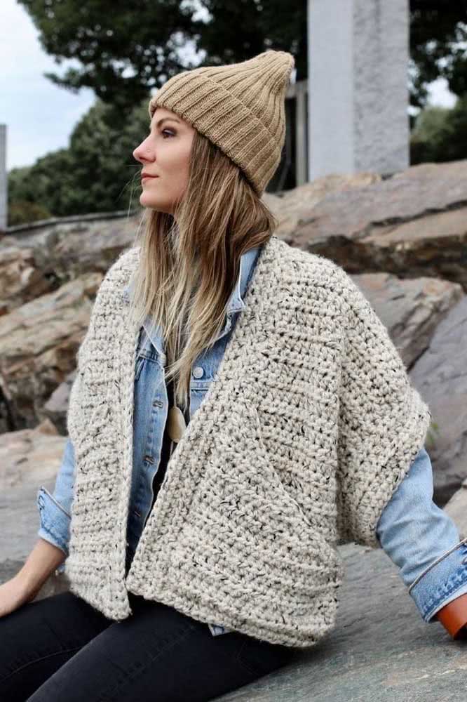 O bolero de crochê vira uma camada extra de proteção e de estilo contra o frio do inverno nesse look incrível com jaqueta jeans e gorro de tricô. 