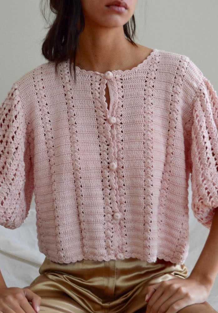 Delicadeza e sofisticação são as duas palavras certas para definir esse bolero de crochê rosa claro com mangas médias bufantes e botões. 