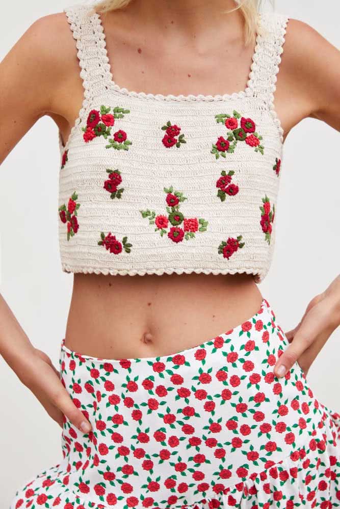 Combinação certeira desse look de cropped de crochê branco com flores vermelhas bordadas e saia de tecido com as mesmas cores e motivo.