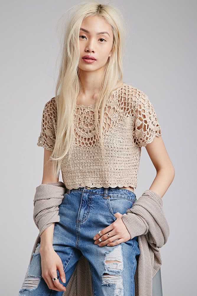 No estilo Hi-Lo, uma combinação de cropped de crochê bege super delicado e com pontos vazados na parte superior e uma mom jeans destroyed. 