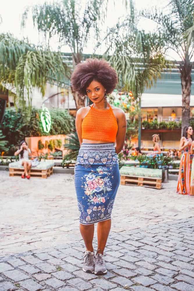 O look perfeito para curtir e passear no dia de verão, com cropped de crochê laranja justinho combinado com uma saia lápis azul floral e tênis bem confortável.