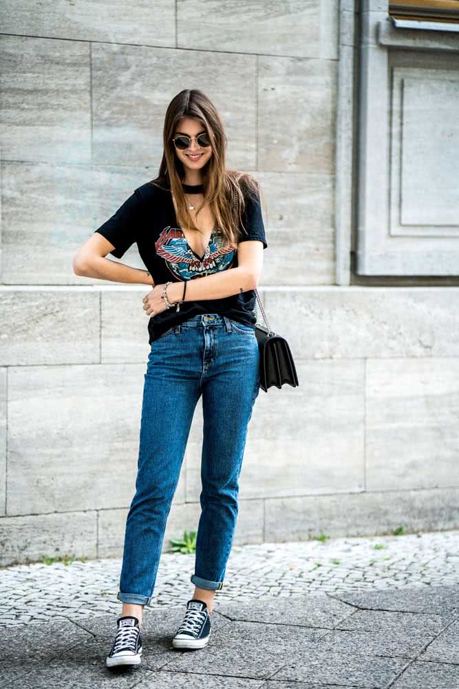 O clássico all star completa este look de mom jeans com a barra dobrada com camiseta preta com decote em V cortado nada básico.