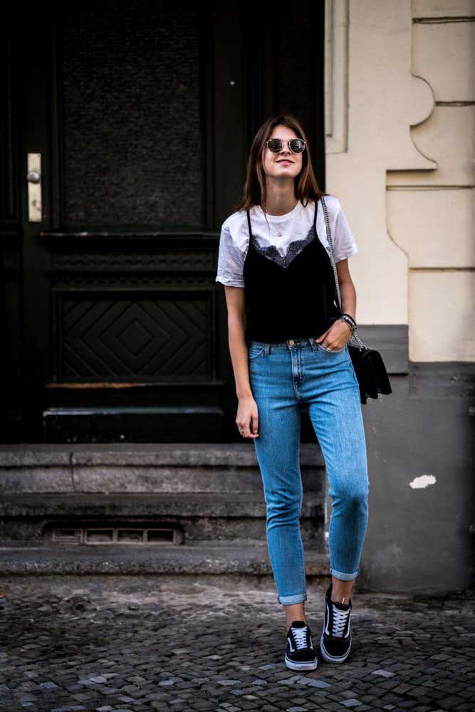 Quer combinar sua mom jeans com outras tendências dos anos 1990? Então confira uma ideia com sobreposição de regata preta e camiseta branca.
