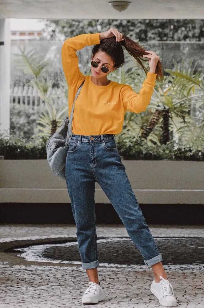 Com blusa de moletinho amarelo mostarda e tênis casual branco, um look com calça mom jeans perfeito para o estilo tumblr. 